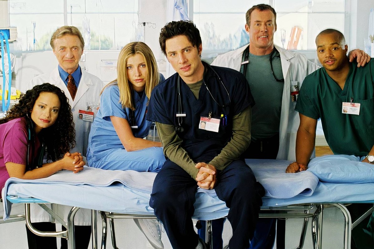 Die Originalbesetzung von Scrubs im Krankenhaus; J.D. steht im Zentrum, Dr. Cox ist im Hintergrund zu sehen.